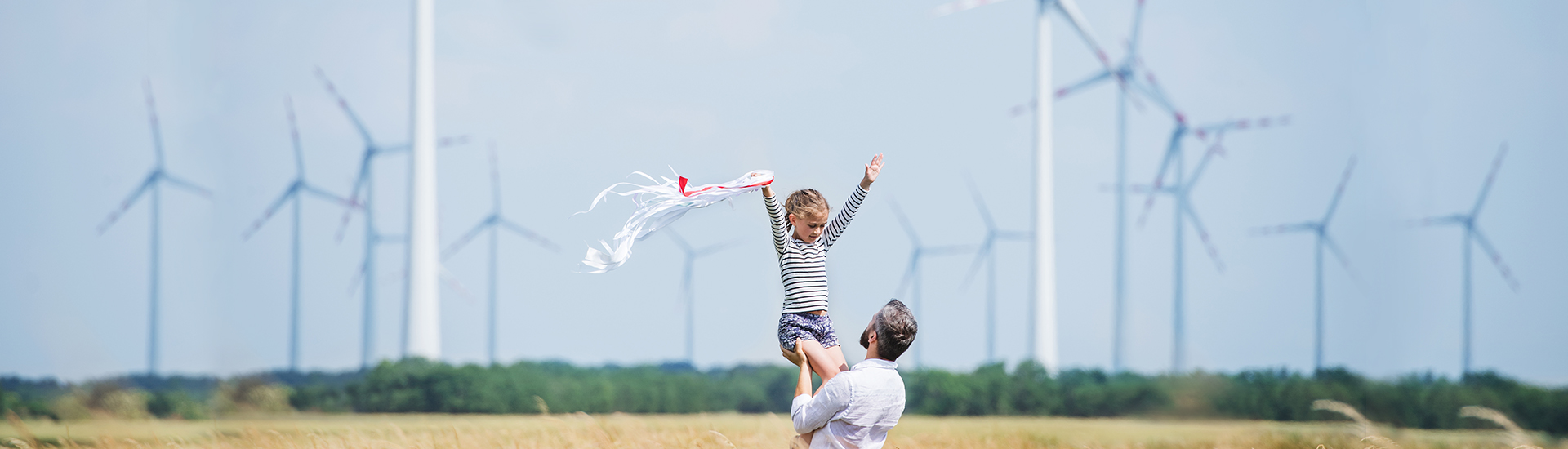 Ellerini havaya kaldırarak rüzgar güllerinin önünde babasıyla poz veren kız çocuğu fotoğrafı yer almaktadır.
